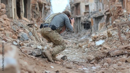 War correspondent crouching among the rubble of a bombed city and taking pictures of the ruins