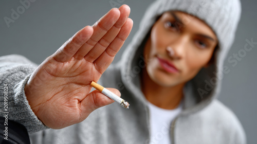 Young person refusing a cigarette with a stop hand gesture for anti smoking campaign and health awareness banner or poster background