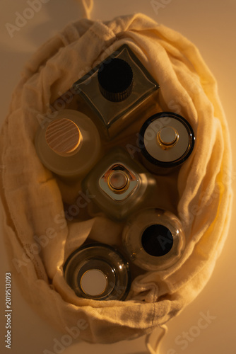 Top Down View Of Various Glass Skincare Bottles Inside Reusable Muslin Drawstring Pouch