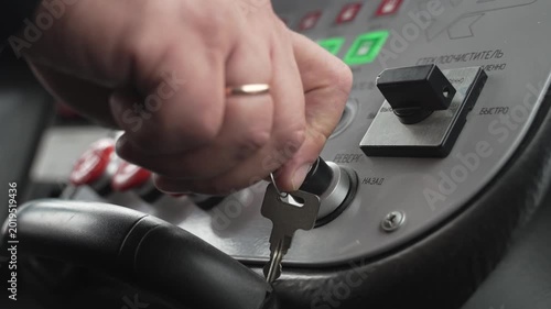 Tram driver turns metal key and starts the vehicle. The car's dashboard features sensors and illuminated buttons.