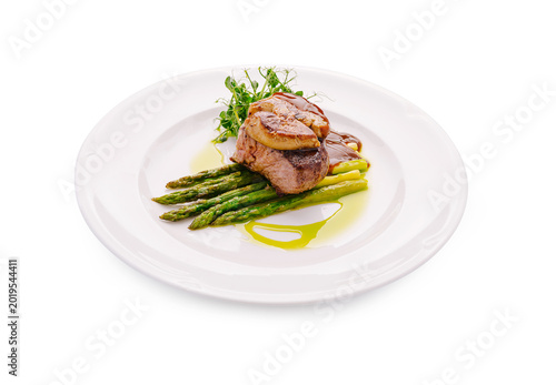 Beef tenderloin steak Rossini with foie gras and asparagus served on a white plate at a restaurant