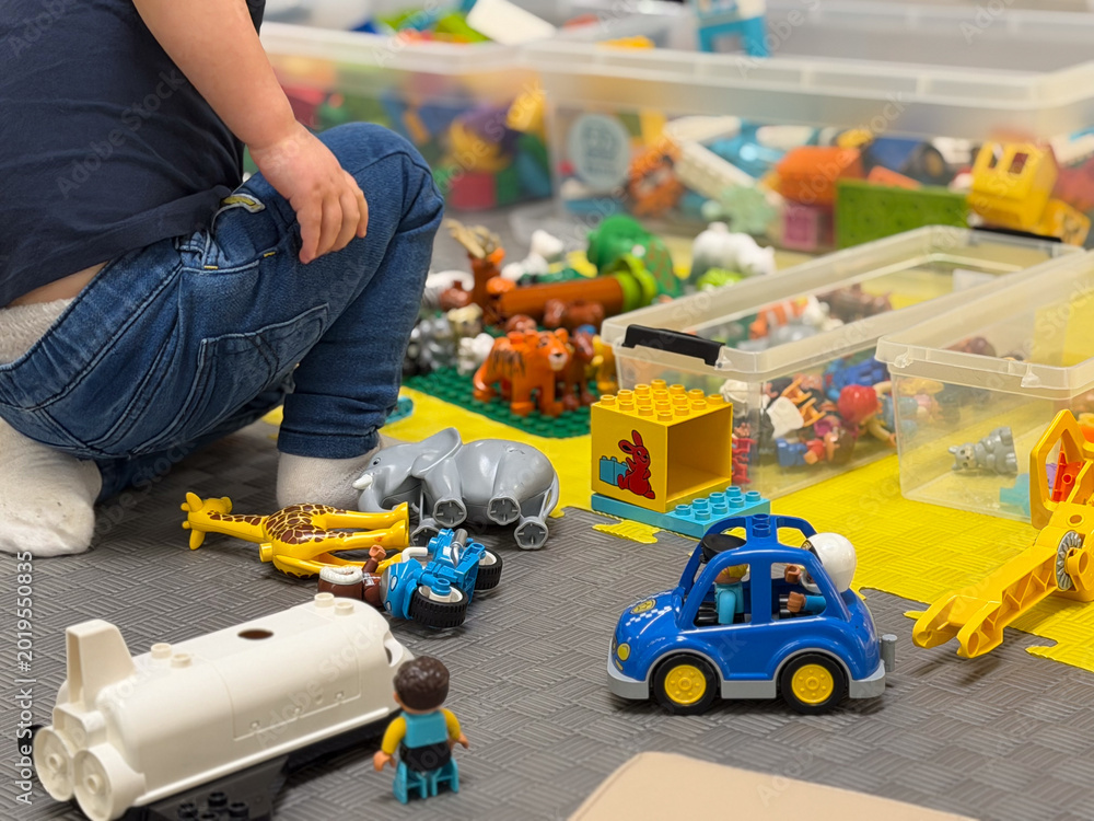Fototapeta premium Child Playing on Floor with Toys and Storage Bins lego