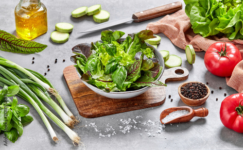 Fresh mixed green salad in bowl with basil and vegetables