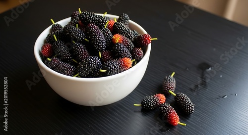 Fresh mulberries in white bowl on black surface natural food photography