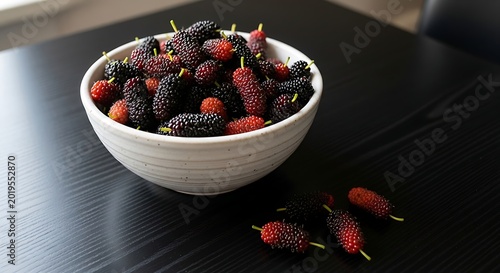 Fresh mulberries in a white bowl on a dark surface natural light