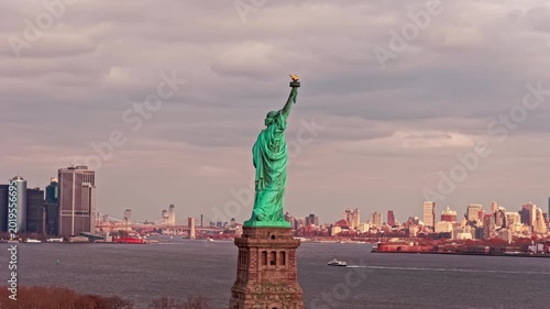 Liberty monument framed by the New York City skyline. Statue of Liberty in New York City view. Liberty statue near New York City harbor area. New York City panorama with famous Liberty monument.