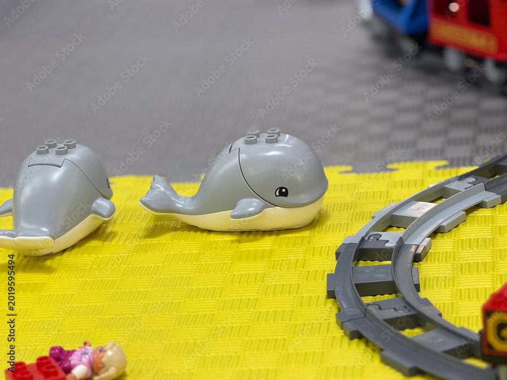 Fototapeta premium Toy whales on yellow playmat with train tracks lego