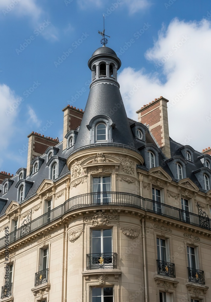 Fototapeta premium Classic Haussmann Architecture in Paris with Ornate Stone Facade and Turret under Blue Sky