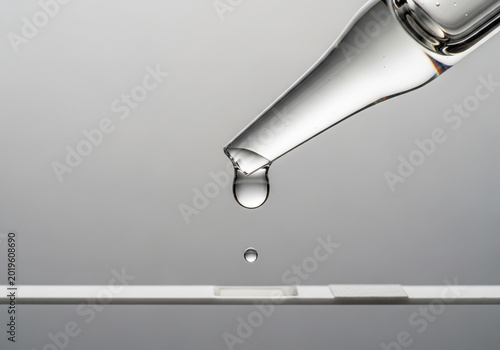 Glass Pipette Dripping Liquid Sample onto Medical Rapid Test Strip