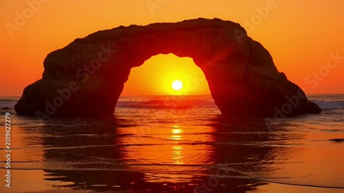 Sunset over ocean rock arch.