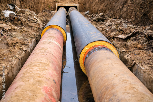 Tableau sur toile Excavated trench with old worn heating pipes and new insulated pipeline section