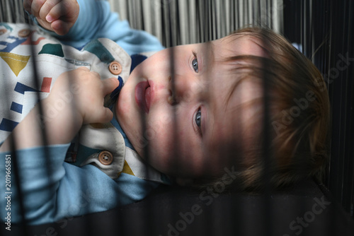 Bild auf Leinwand smiling young child playing in his playpen outside
