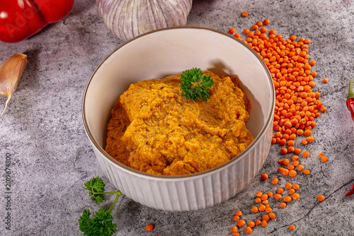 Photos Spicy red lentil dip in bowl with fresh bell pepper garlic and chili on grey bac