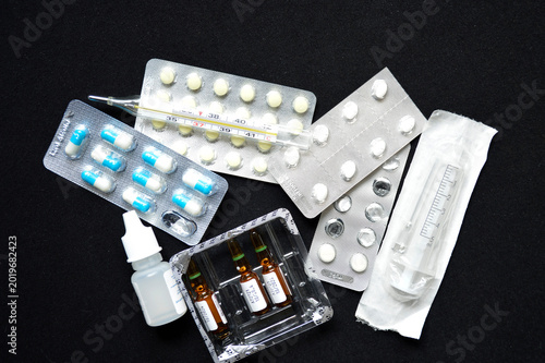 syringe, ampoules with medicines and pills on a black background. treatment during illness or disease prevention. injections with medicines or vitamins