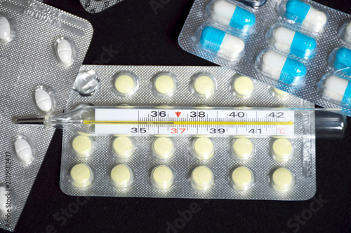 syringe, ampoules with medicines and pills on a black background. treatment during illness or disease prevention. injections with medicines or vitamins