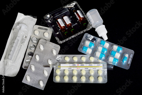 syringe, ampoules with medicines and pills on a black background. treatment during illness or disease prevention. injections with medicines or vitamins