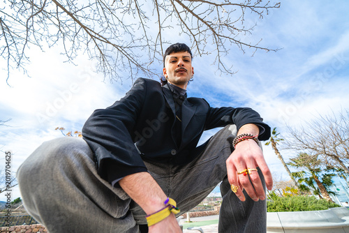 A low-angle shot of a young adult crouching and looking at the camera in an outdoor park