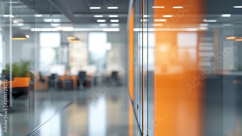 A blurred view of a modern office interior with orange accents and glass walls