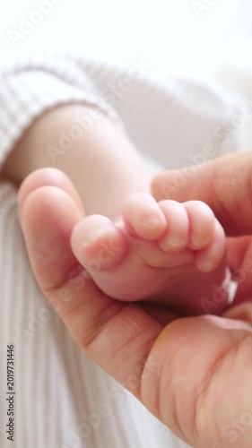 Closeup of a parent's hand tenderly holding the tiny, delicate foot of a newborn baby, a beautiful and heartwarming moment symbolizing family love, care, and the beginning of a new life