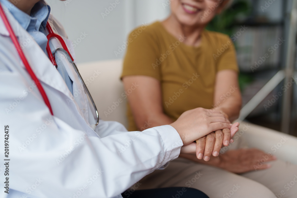 Obraz premium Medical doctor provides comforting support by holding a senior woman's hand, demonstrating empathy and trust during a healthcare appointment or wellness check