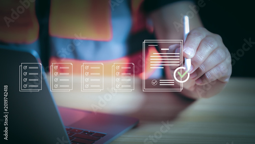 Engineer using stylus pen signing digital document for online approval and safety inspection checklist. Quality control management, compliance, and smart construction technology concept.