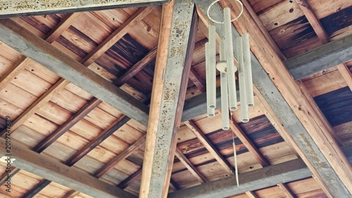 Foto Metal wind chime hanging under wooden pavilion roof, breeze creating crisp sooth