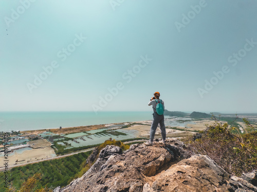 Fotografia Person standing on rugged cliff observing distant island landscape