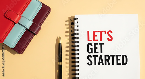 A spiral notebook with a pen and a leather journal on a yellow background with the words lets get started