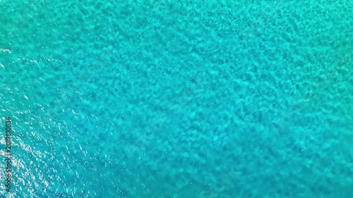Turquoise rippling water background texture. Caribbean Sea waves on a bright sunny day. Bird's-eye view. Sea surface with reflected sunlight. Sea voyage. Water landscape.