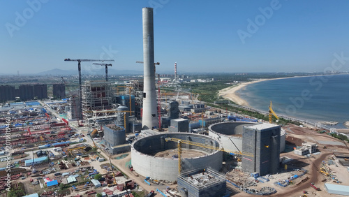 Foto Coastal thermal power plant under construction with cooling towers and smokestac