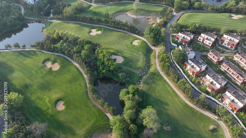 Foto Aerial view of a golf course with residential villas surrounded by green lawns,