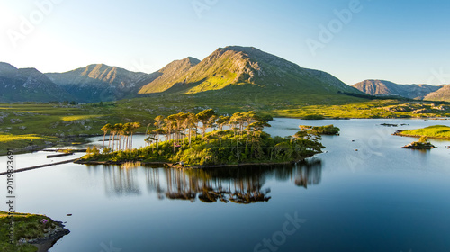 Schilderij op canvas Aerial view of Twelve Pines Island resting in still water on Derryclare Lough beneath the Connemara mountains, County Galway