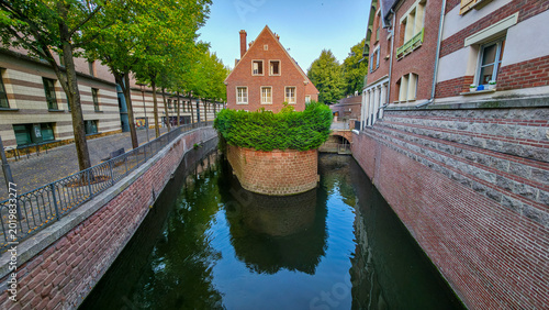 Small channel surrounded by buildings and green plants in Amiens offers a view of the waterway and architecture during the day