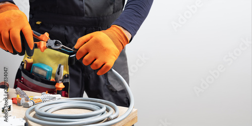 Photos Electrician at work with nippers in hand cut the electric cable