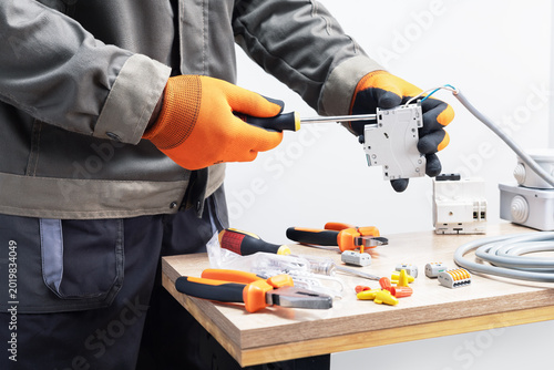 Electrician in gloves working with circuit breaker.
