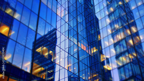 Konstfotografi Modern glass facade of a skyscraper with blue sky and city building reflections,