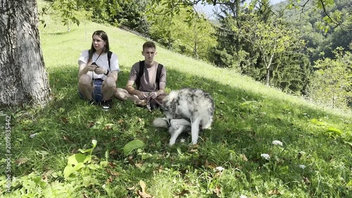 Young hikers with husky dog enjoying nature and exploring landscape with binoculars in forest meadow