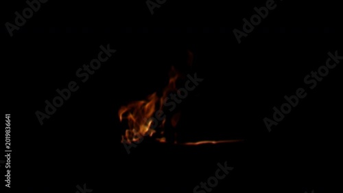 A small isolated fire with bright orange flames flickering intensely against a solid black background.