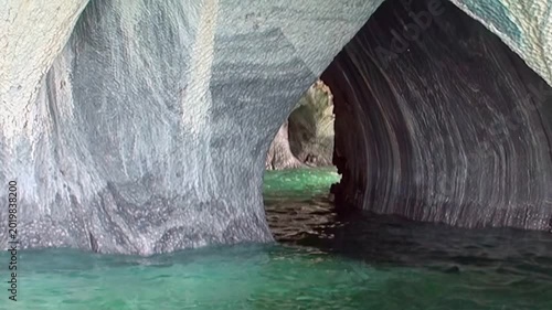 A serene journey glides through Patagonia's majestic Marble Caves. Witness nature's artistry where smooth, swirling marble walls meet dazzling turquoise waters on a bright day.
