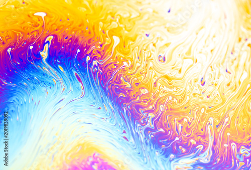 Vibrant iridescent soap bubble surface with swirling patterns of blue, purple, and yellow