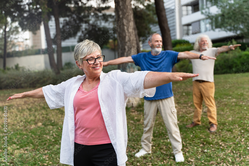 Obraz premium Senior healthy people doing yoga outdoors, at the urban park