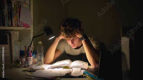 Teenager studying with tired eyes and phone distractions nearby ,stressed work in office, upset student in his room, student studing at night with stress, hard work of office worke