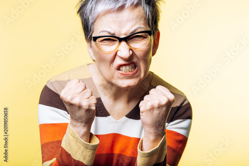 Foto Senior woman clenching her fists, expressing intense anger and frustration while