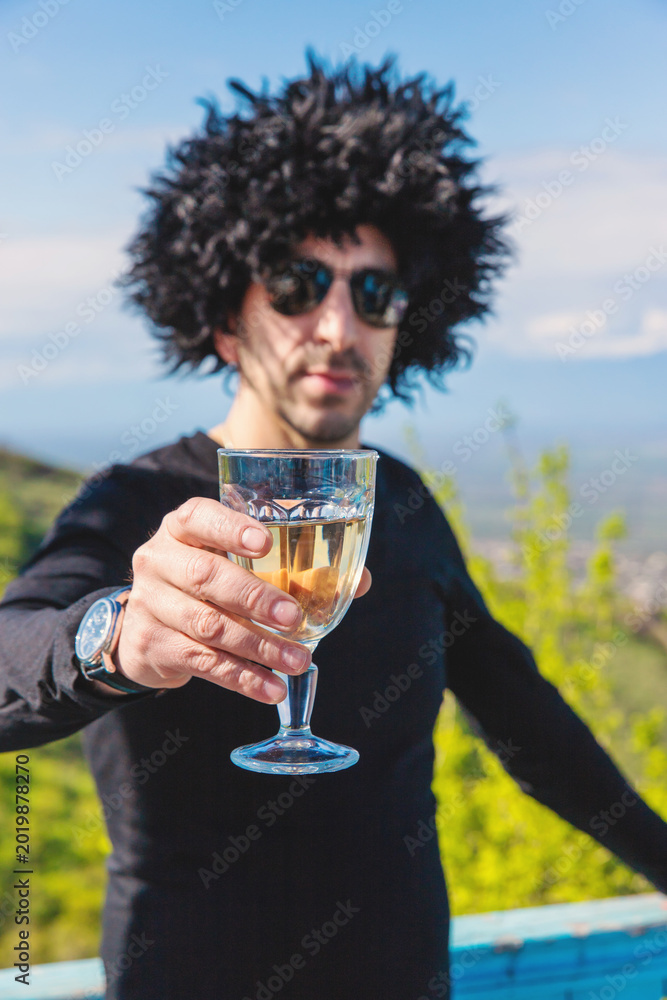 Fototapeta premium Georgian man in a papakhi with a glass of wine. Selective focus.
