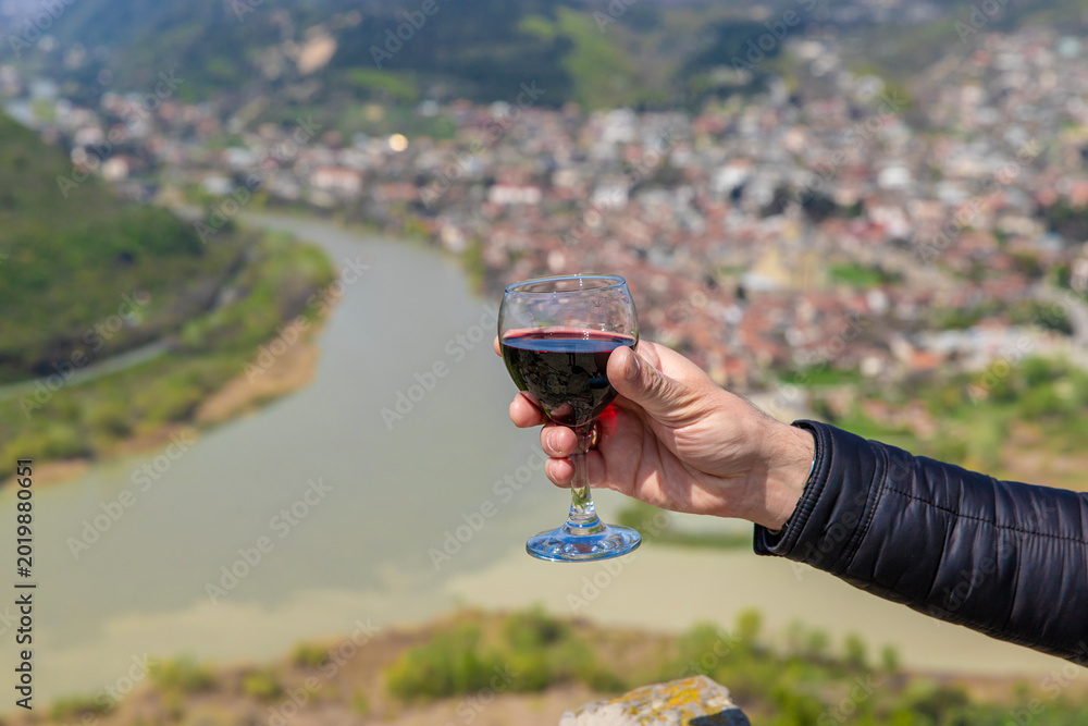 Fototapeta premium Georgian man in a papakhi with a glass of wine. Selective focus.