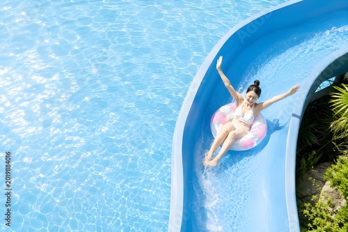 夏のウォータースライダーではしゃぎながら楽しそうに遊ぶ若い女性の爽快なレジャーイメージ（AI生成）