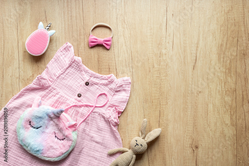 Quadro su tela Baby girl pink cotton muslin dress and unicorn-shaped accessories, top view
