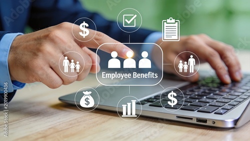 Close up of hand touching employee benefits icon on laptop keyboard surrounded by symbols of money family insurance and healthcare representing human resources compensation