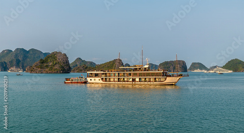 Fotografie A view of a cruise ship passing Karst limestone islets into a lagoon in Ha Long
