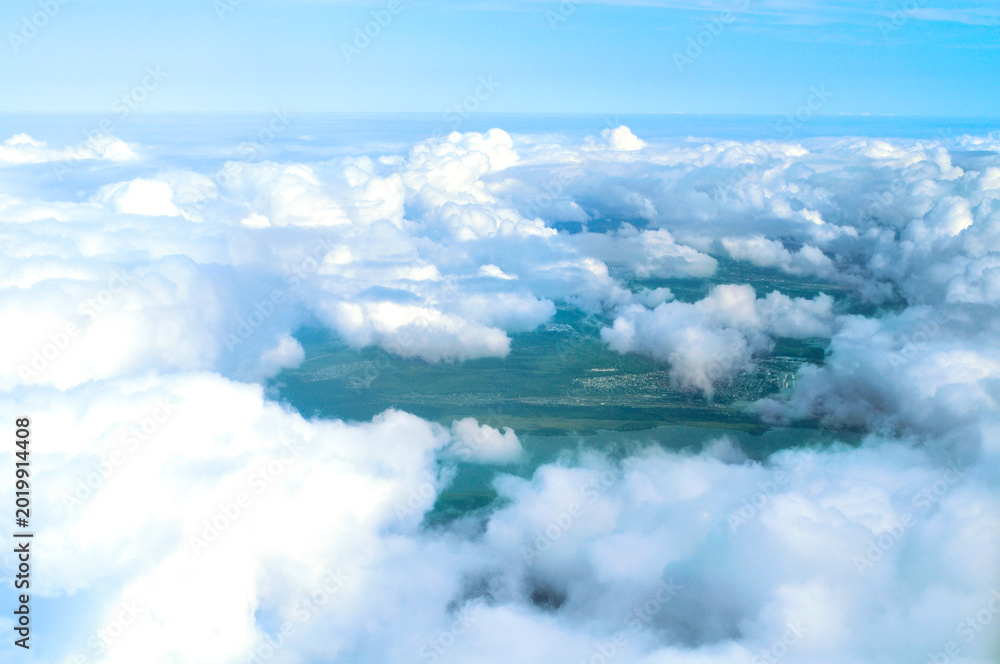Obraz premium Aerial window view of the clouds, cloudscape of white dense clouds floating over land surface, summer travel by air concept